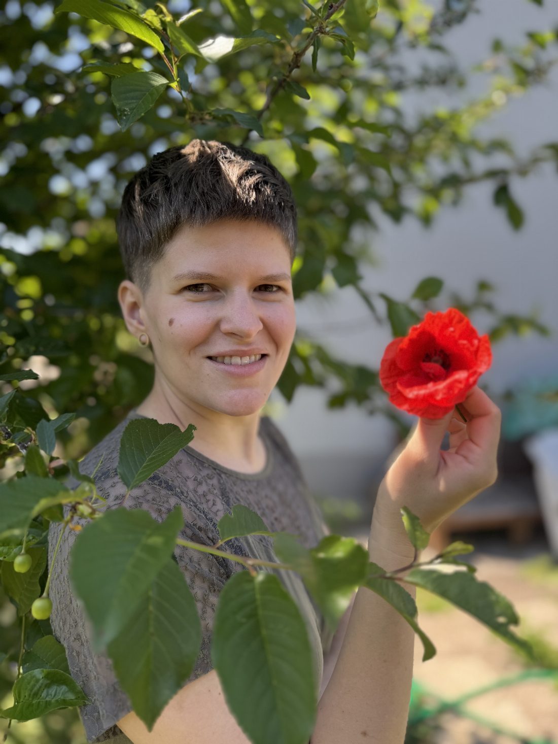 Marleen Moharitsch im Garten mit einer roten Mohnblume in der Hand